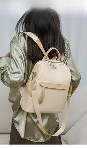 Rear view of model wearing a lightweight beige nylon backpack with brown leather accents
