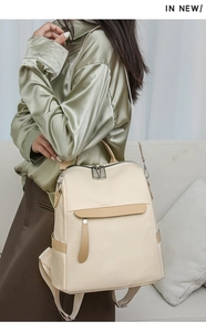 Model wearing a large beige nylon backpack with camel trim in a cozy indoor setting