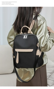 Detail of black nylon backpack with beige trim and detachable shoulder strap on model