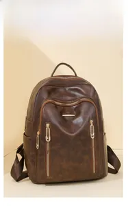 Detail of dark brown vintage faux leather backpack with multiple gold zippers and textures