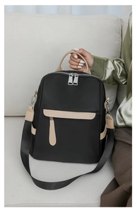 Detail view of black oxford fabric backpack with beige leather trim and double zippers