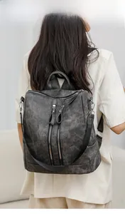 Detail view of a dark grey textured backpack with double zippers worn by a model