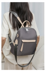 Detail of grey oxford fabric backpack with beige leather handles and detachable strap