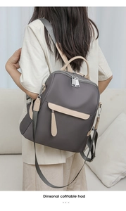 Close-up of stylish grey Oxford cloth backpack worn by a model in a cozy home setting