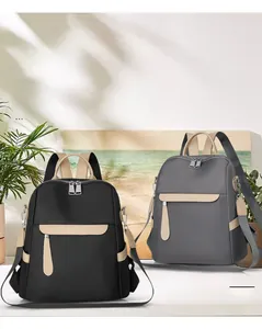 Close-up of black and grey oxford fabric backpacks with stylish brown handles and zippers