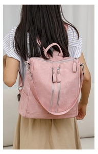 Close-up of pink faux leather backpack with double zippers worn by a model in casual attire