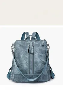 Detail of blue denim backpack showing functional double vertical zippers and robust metal hooks