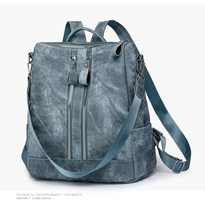 Detail view of blue-grey denim textured backpack with dual vertical zippers and handle