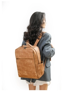 Side view of a vintage brown PU leather backpack with dual zippers and large front pocket