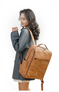 Man in a grey suit wearing a large brown PU leather backpack with double zippers
