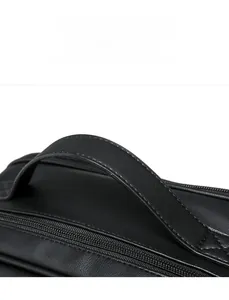 Close-up of the reinforced PU leather handle and metal zipper on a black vintage backpack