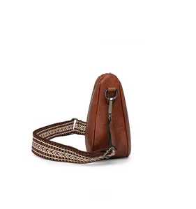 Side view of brown faux leather crossbody bag with geometric pattern wide strap