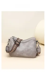 Detail of grey crossbody bag featuring textured faux leather and ethnic woven strap