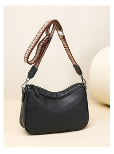 Detail of black pebbled leather crossbody bag with ethnic style woven wide shoulder strap
