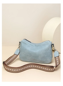 Close-up of light blue hobo bag with patterned ethnic shoulder strap and soft texture