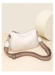 Close-up of beige faux leather bag featuring a colorful woven shoulder strap and metal hardware