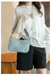 Detail of grey-blue shoulder bag with ethnic style woven wide strap on female model