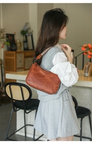 Brown vintage shoulder bag with geometric woven strap shown on a model in a café