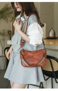 Close-up of vintage brown leather crossbody bag with woven ethnic style wide shoulder strap