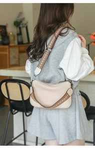 Detail of beige crossbody bag featuring bohemian geometric patterned wide strap and soft texture
