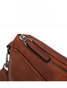 Detail of leather zipper pull and litchi grain texture on brown crossbody bag