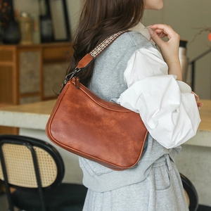 Retro brown shoulder bag with a stylish geometric woven strap shown on a model
