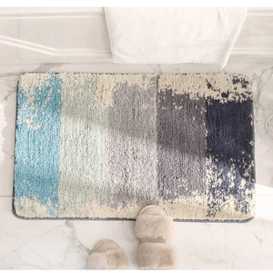 Détail du tapis de bain moelleux dégradé bleu et gris sur carrelage en marbre