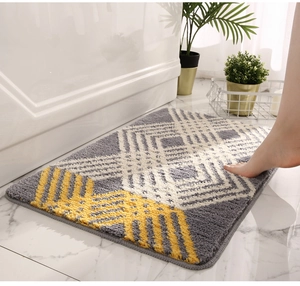 Close-up of geometric grey, white and yellow plush bath mat by a bathtub on marble floor
