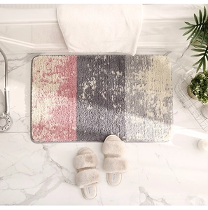 Gros plan d'un tapis de bain moelleux rose et gris sur un sol en marbre chic