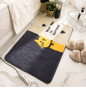 Close-up of plush grey bathroom mat with yellow cat pattern on marble floor