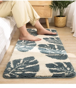 Primer plano de alfombra suave con hojas de monstera azules siendo pisada por pies