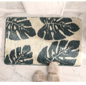 Primer plano de alfombra de baño de hoja de monstera con textura suave sobre mármol