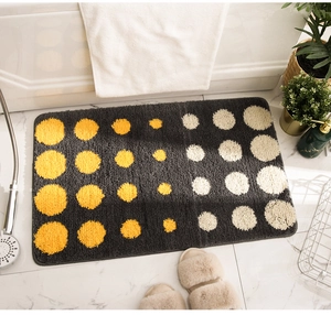 Dettaglio del tappeto da bagno assorbente con pois gialli su pavimento in marmo