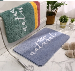 Dettaglio del tappetino da bagno assorbente con scritta natural e trama in peluche denso