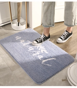 Dettaglio del tappeto da bagno azzurro in microfibra con scritte bianche su legno