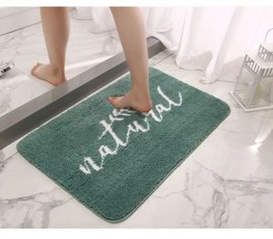 Dettaglio del tappetino da bagno verde scuro con motivo a foglie bianche e trama morbida