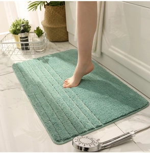 Detalle de alfombra de baño verde mostrando su textura de rayas gruesas y fibras suaves