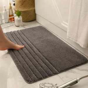 Detalle de alfombra de baño gris oscuro con rayas suaves sobre suelo de mármol