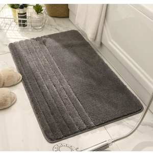 Alfombra de baño gris oscuro de microfibra con textura suave y rayas junto a la bañera blanca