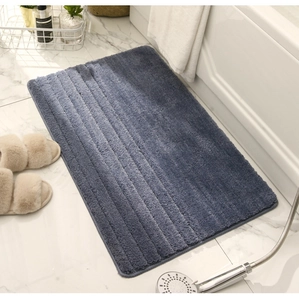Detalle de la alfombra de baño absorbente gris azulado en chenilla junto a bañera