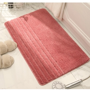 Detalle de alfombra de baño rosa afelpada con líneas esculpidas en suelo de mármol