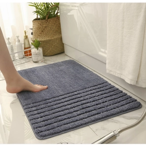 Detailed view of the thick dark grey absorbent bath mat with non-slip texture on marble floor