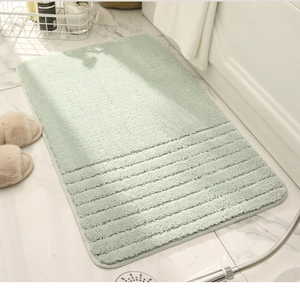 Close-up of soft light green shaggy bath mat with anti-slip texture on marble floor