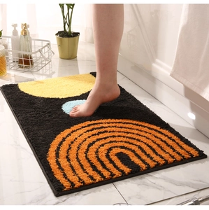 Detailed view of plush geometric bathroom mat with yellow and orange arcs on black base