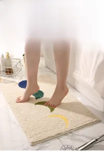 Gros plan de pieds sur un tapis de bain épais et absorbant aux motifs de feuilles