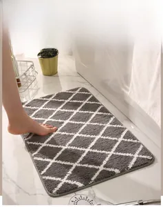 Detailed close-up of dark grey diamond pattern bath mat on marble floor with feet