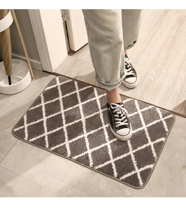 Detail of thickened gray and white diamond pattern door mat on a wooden floor