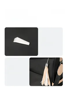 Detail of geometric silver metal buckle and two-tone tassel zipper on black nylon backpack