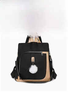 Dettaglio dello zaino in nylon nero con rifiniture in pelle beige e ciondolo a pompon