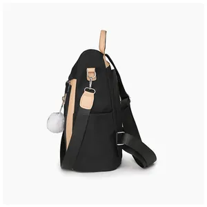 Vista laterale dello zaino in nylon nero con finiture in pelle marrone e pompon bianco